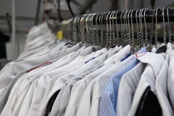 A row of business shirts on a rack at a cleaners