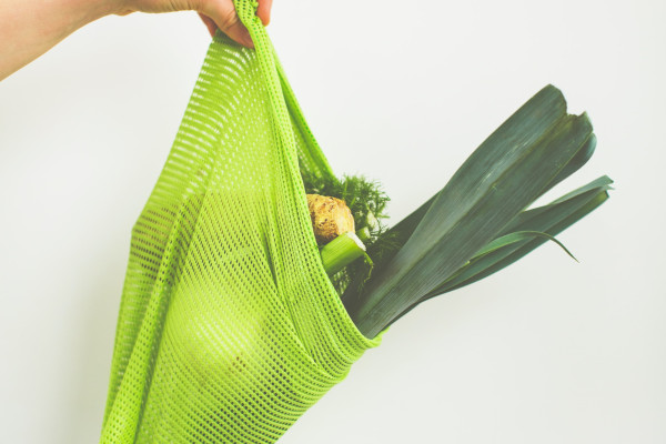 Sustainable green, cotton mesh bag with leeks, and other vegetables inside