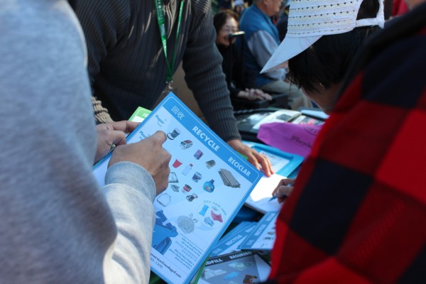 Outreach SFE staff explains to a community member about recycles that belong int he blue bin