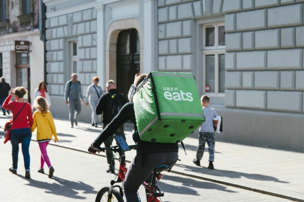 Person riding a bike wearing a large food delivery backpack that's green