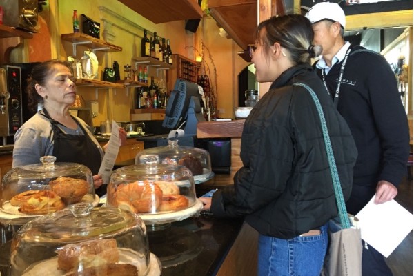 Zero Waste specialist from the Department stands at the counter of a local business speaking to an employee about Zero Waste policies