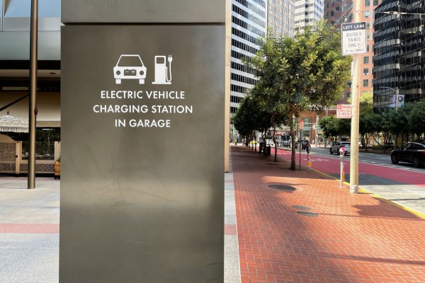sign for electric vehicle charging in front of parking garage