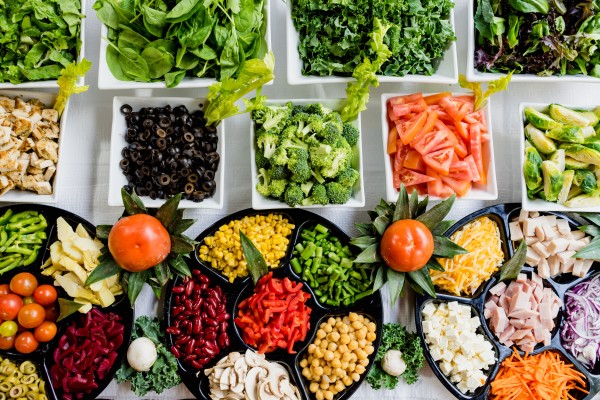 Rows of food mostly vegetables all in separate bowls on a table