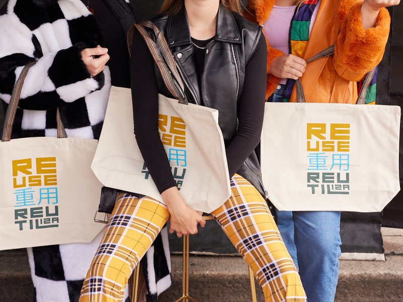 A group of three young people holding three reusable bags