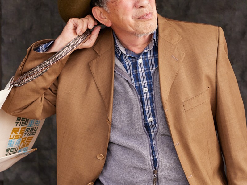 An older man is holding a bag over his right shoulder.