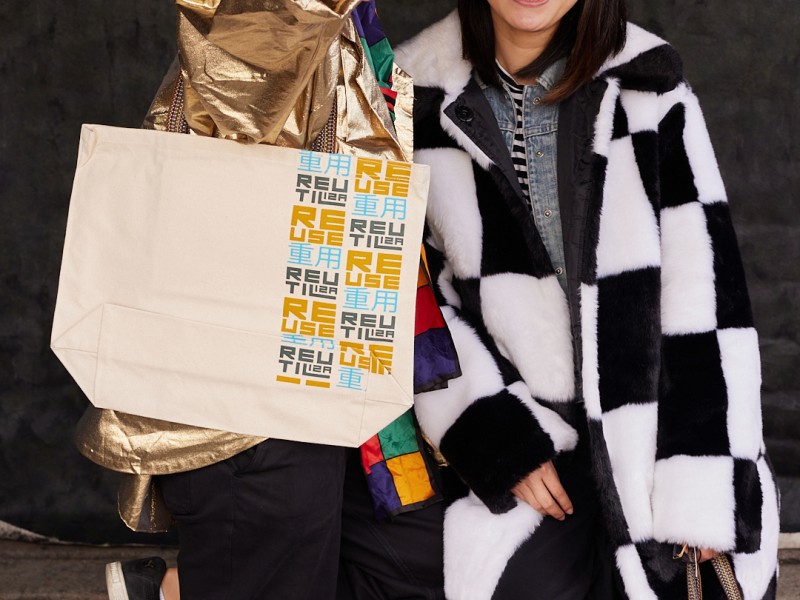 Two individuals pose with their reusable water bottle and shopping bag