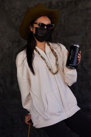 A person wearing a brown hat and black mask poses with a reusable water bottle