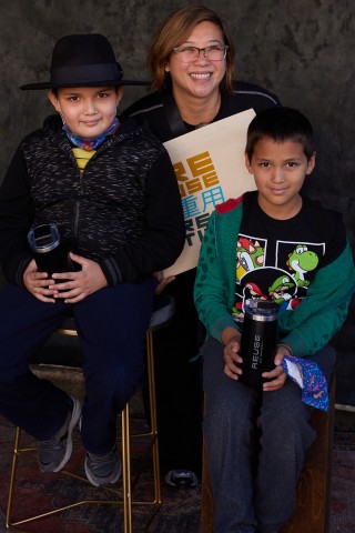 A mother with two young children posing with a reusable bag