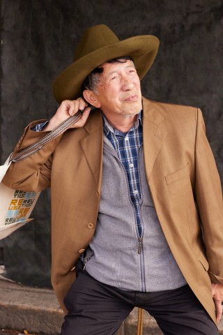 An older man is holding a bag over his right shoulder.