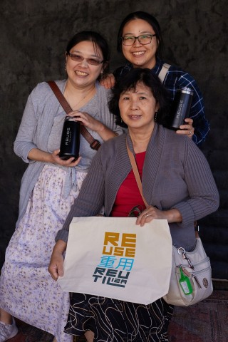 Three individuals pose with their reusable water bottle and shopping bag