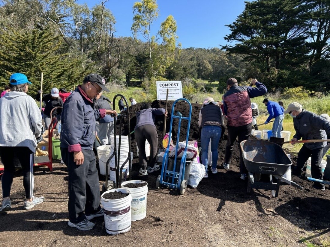 A group of people collecting compost, none are looking into the camera