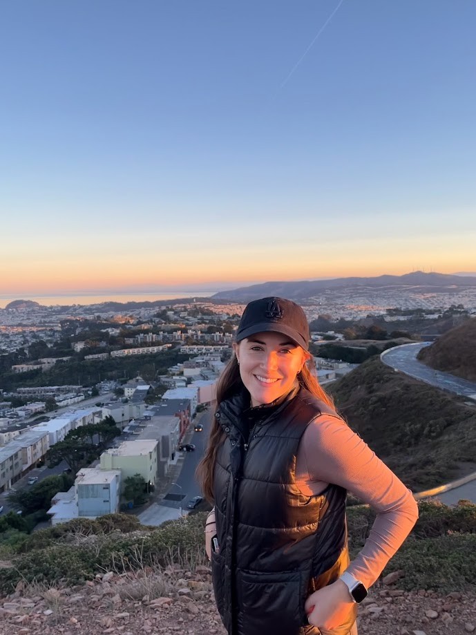 Agustina M. smiling next to a sunset