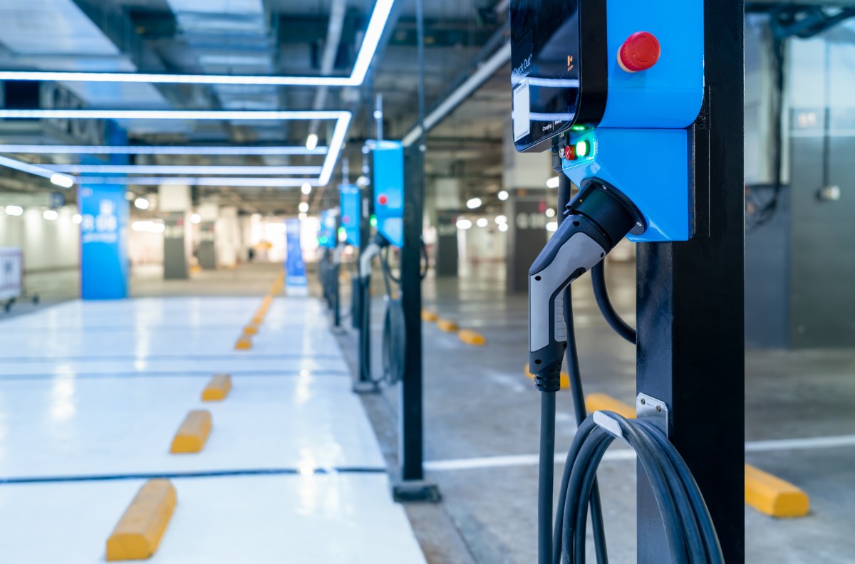 A row of electric vehicle chargers can be seen inside of a parking area of a commercial garage