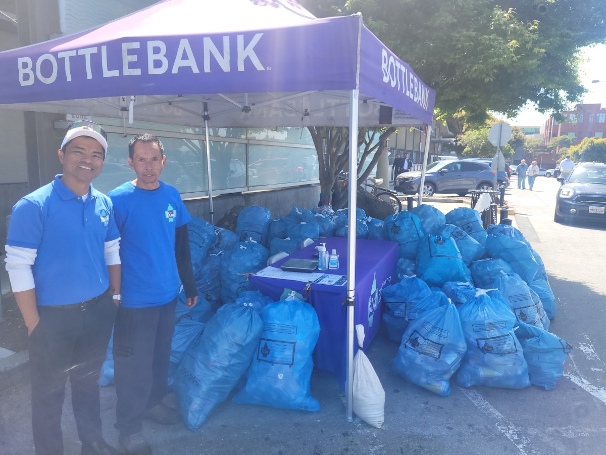 Two BOTTLEBANK employees next to tent with many bags of CRV