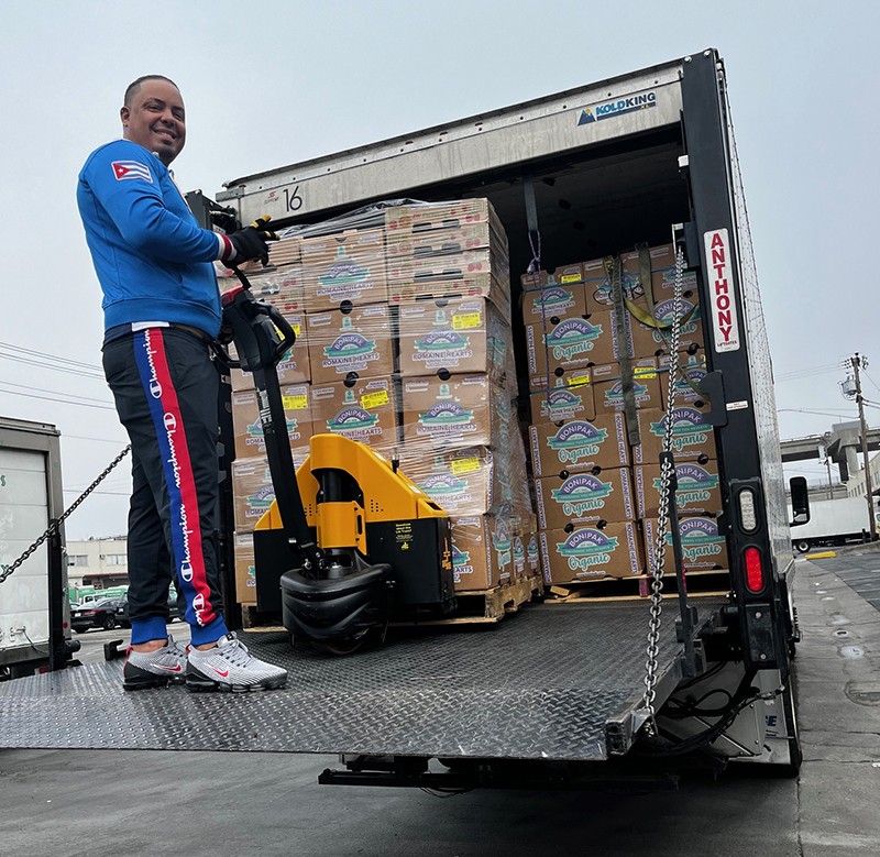 A person on a truck lift moving boxes of food 