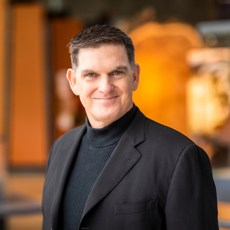 A man with a short haircut wearing a black turtleneck and black blazer