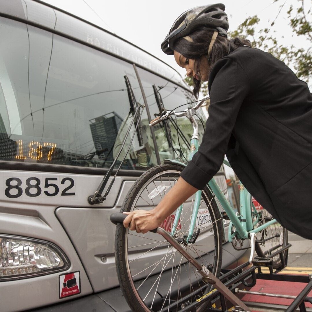 A woman attaches her bike to the front of a Muni bike in San Francisco