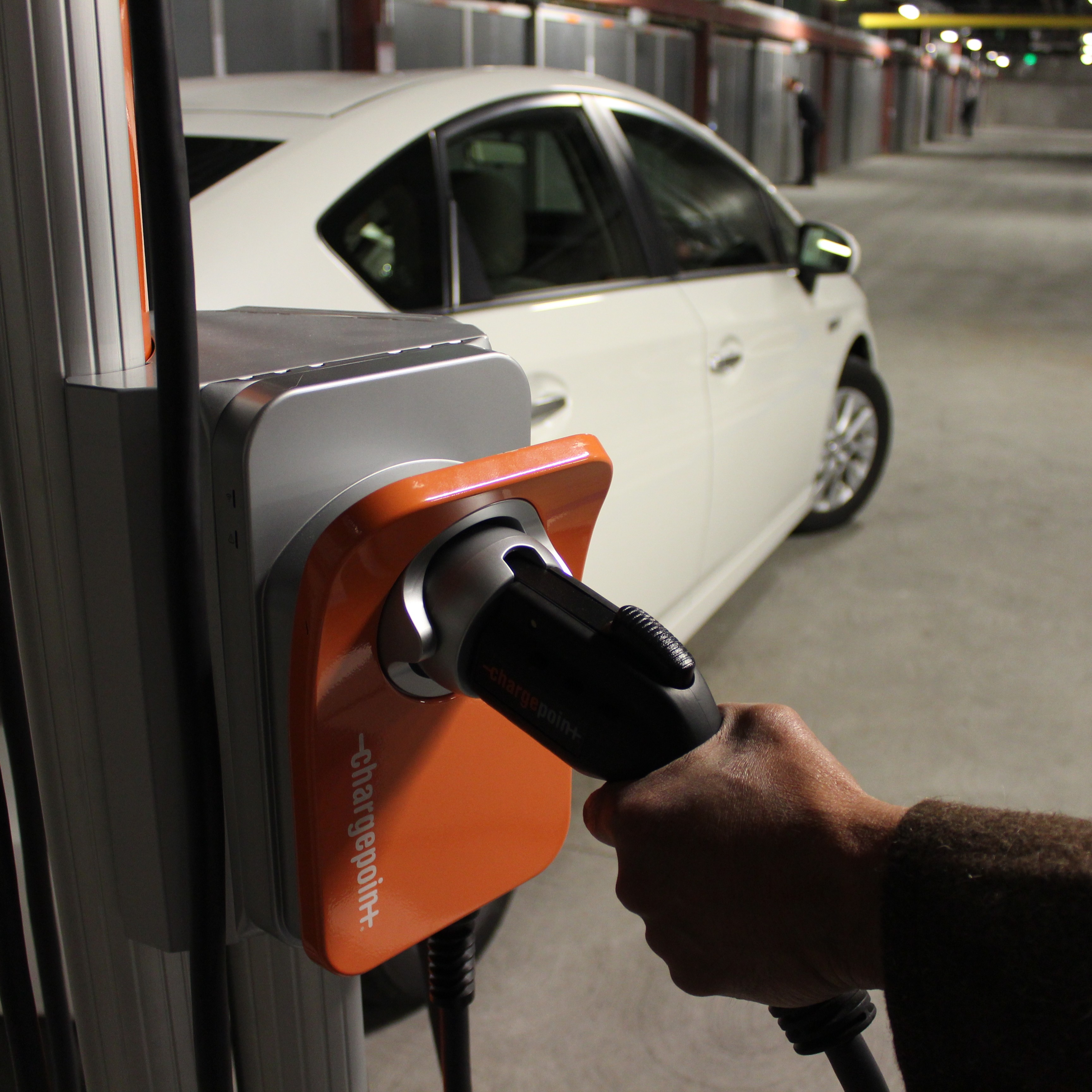 A hand reaches for an electric vehicle charger