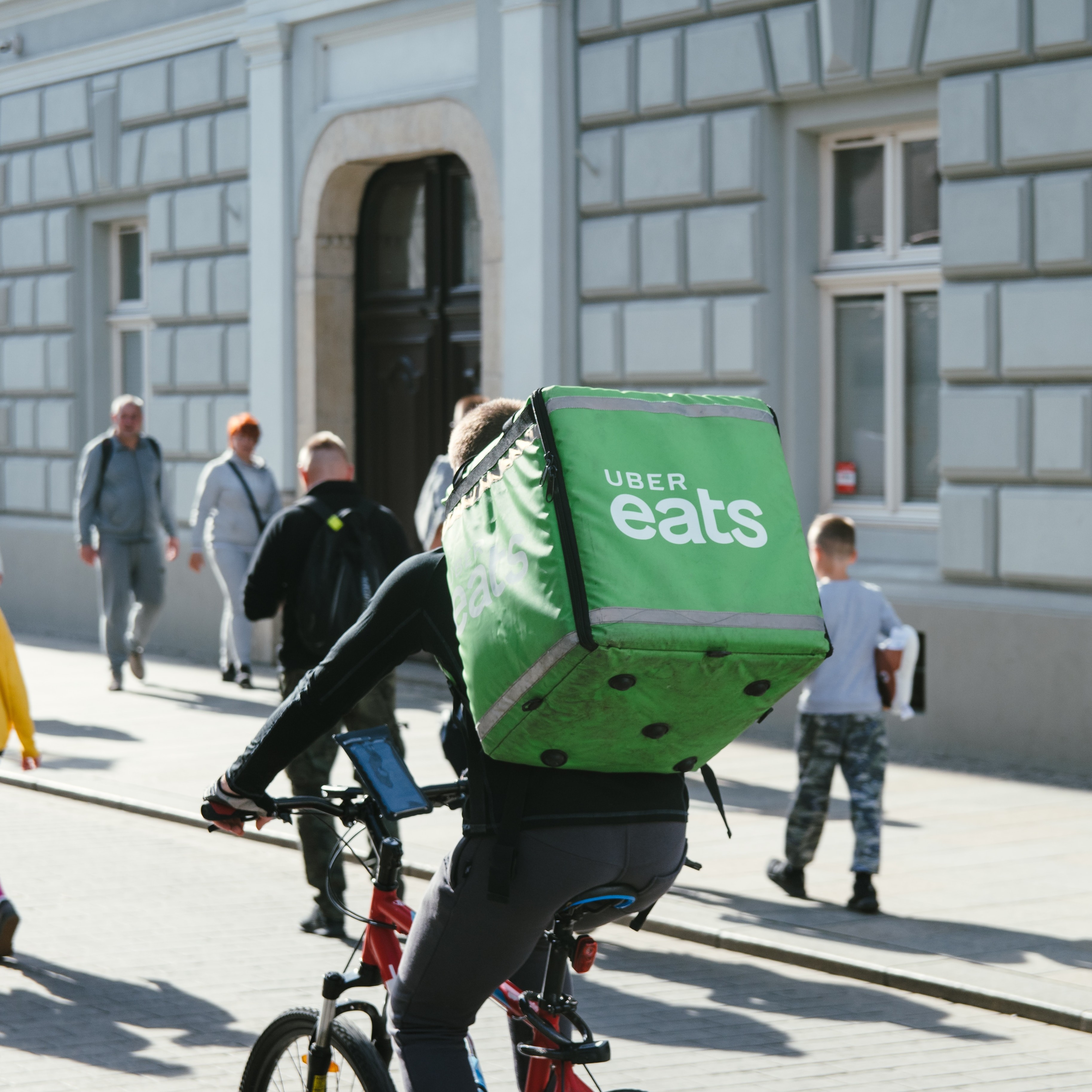 Person riding a bike wearing a large food delivery backpack that's green