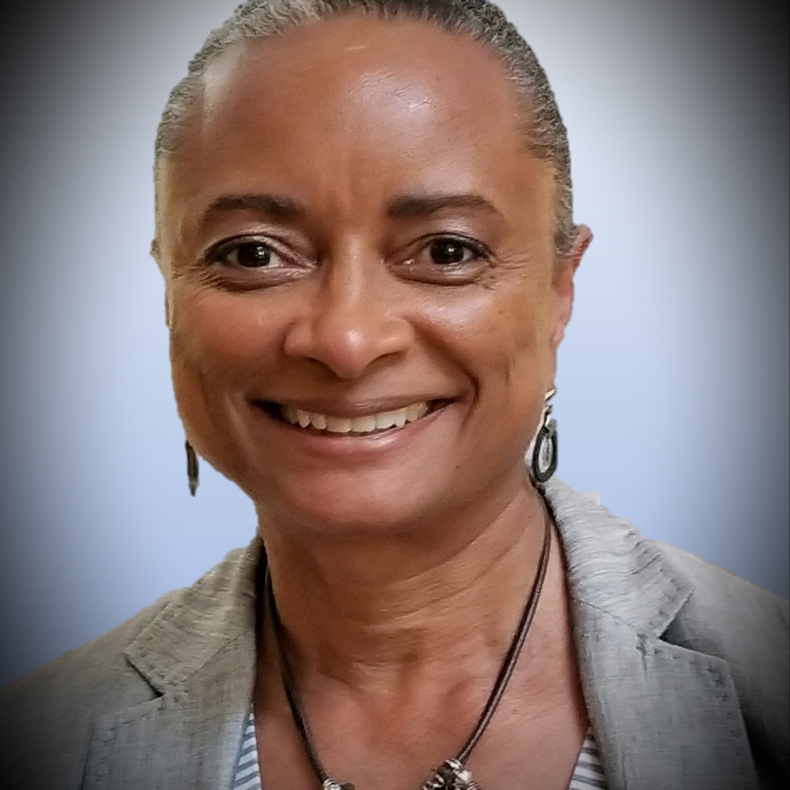 Commissioner Angelique Thompson is smiling, her hair is pulled back and she is wearing a tan jacket