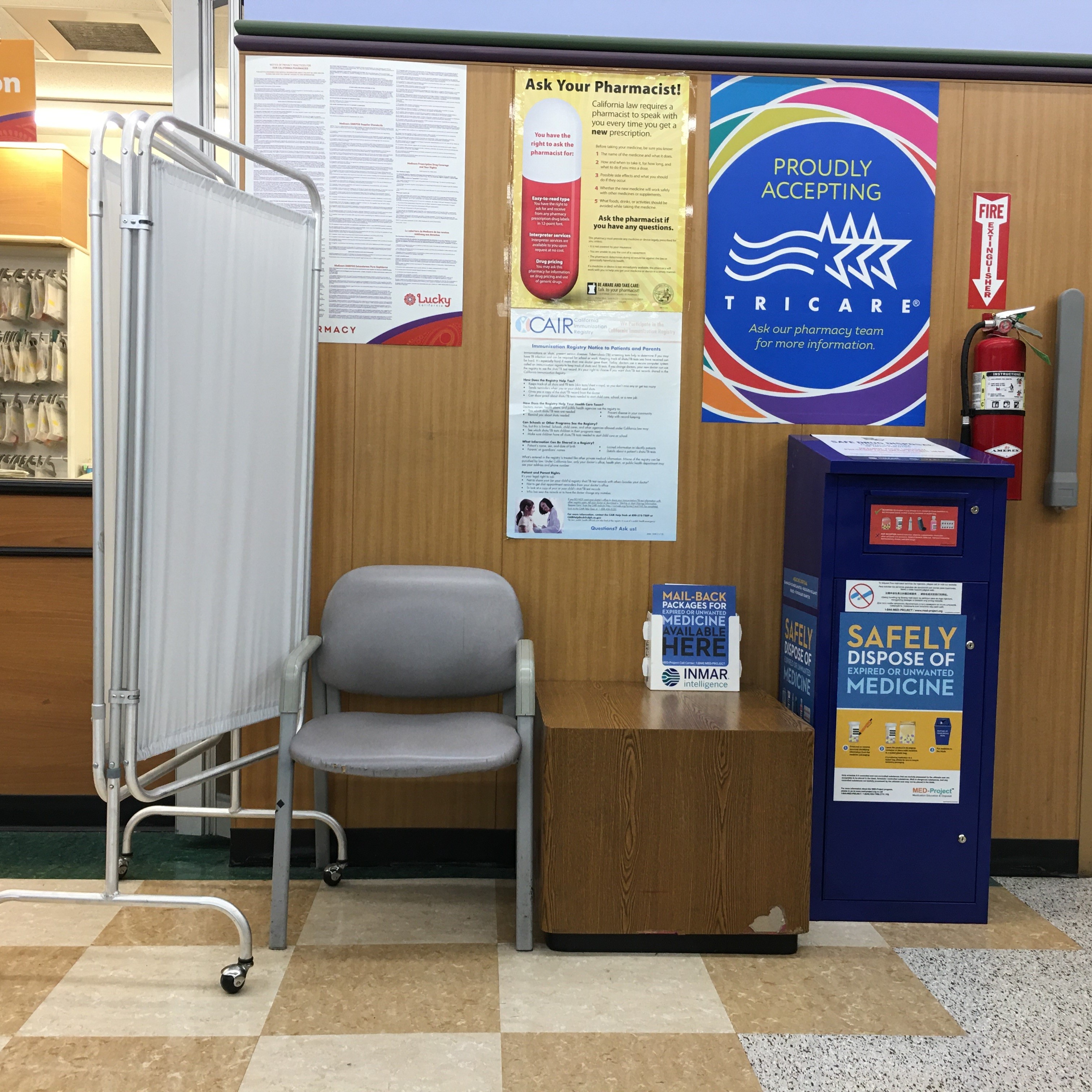 A sitting area of a pharmacy on Fulton street in San Francisco. There is a large blue kiosk for people to safely dispose of unused medicine.