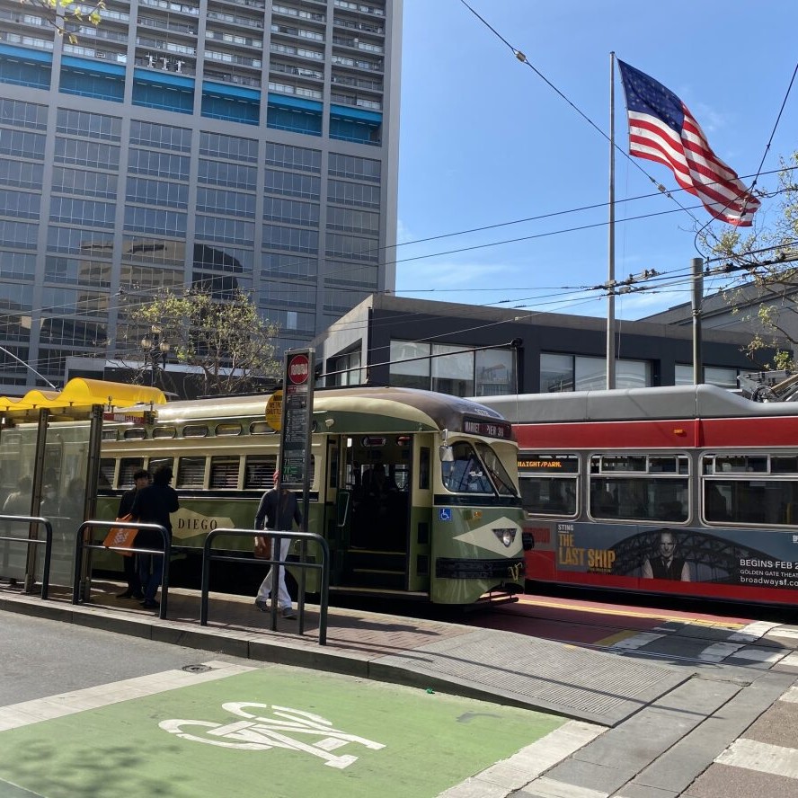 Two San Francisco Muni busses at a stop light on Market street