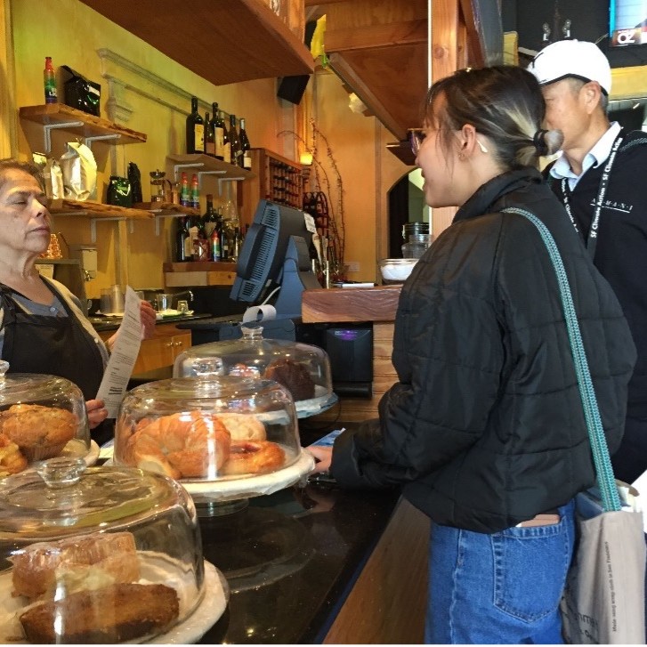 Zero Waste specialist from the Department stands at the counter of a local business speaking to an employee about Zero Waste policies