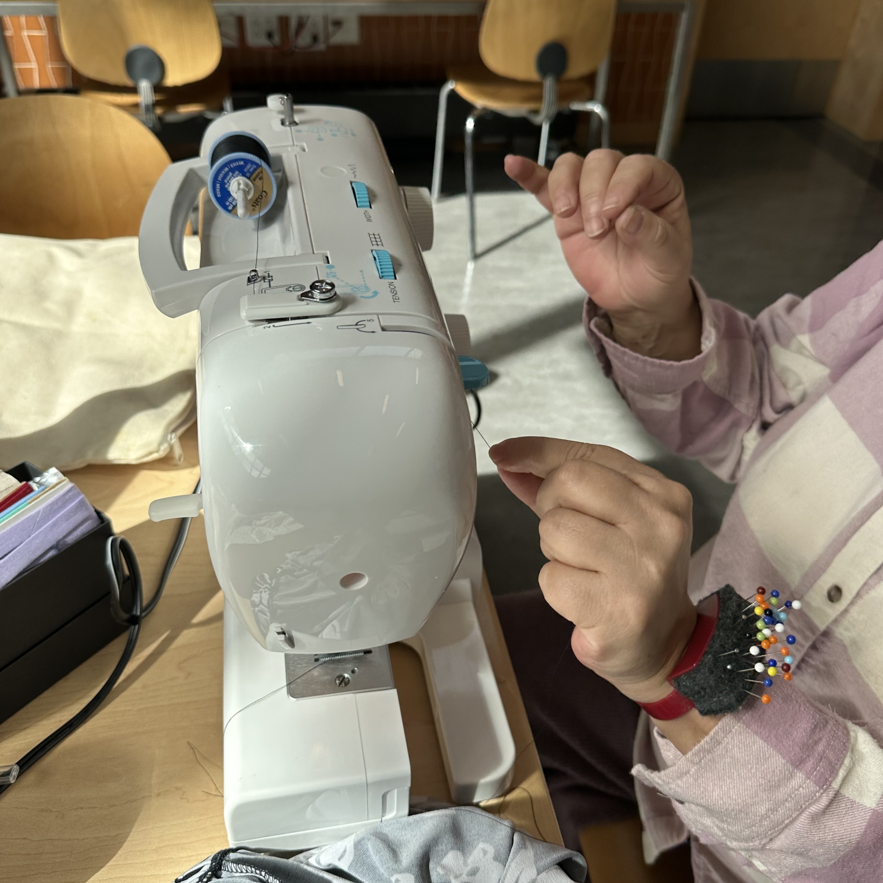 two hands at work with a white sewing machine