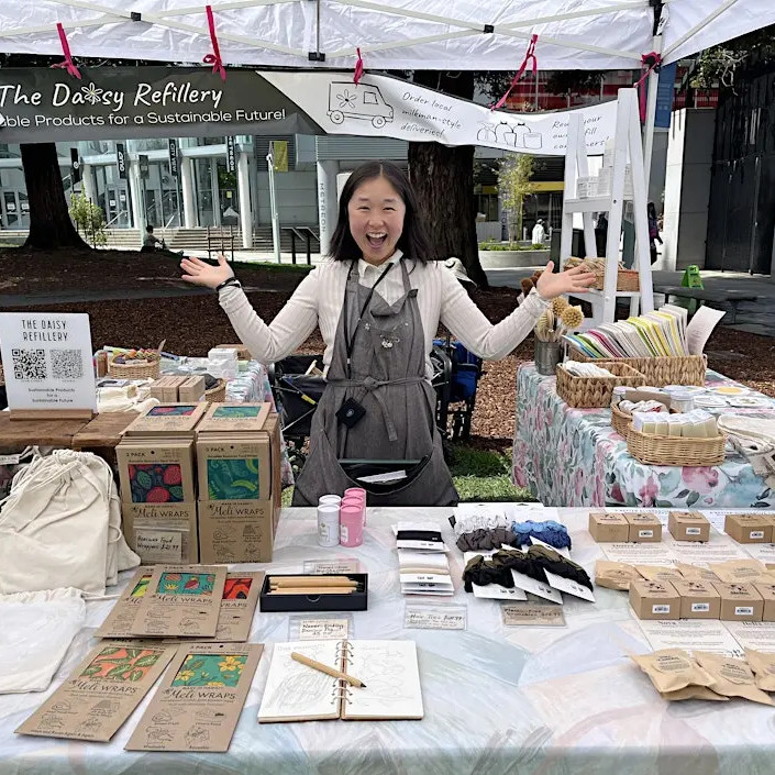 A business owner behind a retail table with their arms outstretched