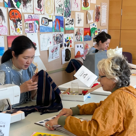 A clothing repair volunteer helps a resident with their clothing item