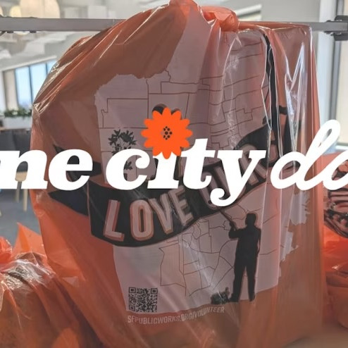 Orange recycle collection bags are stacked on a tan-colored table